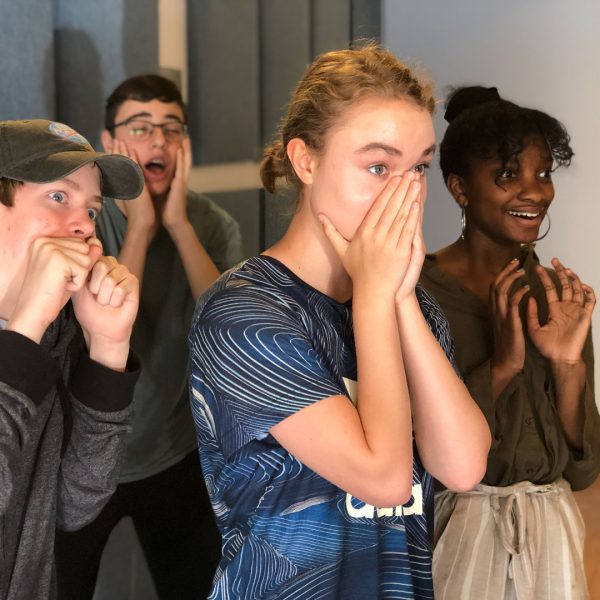 Four teen students making funny faces during a comedy class.